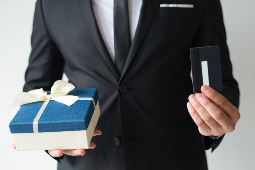 Man in suit holding a gift box and a credit card